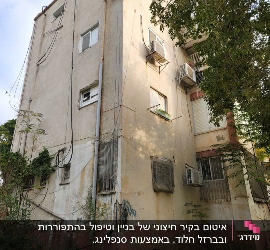אדם על חבל צובע קיר בניין עם דלי צבע